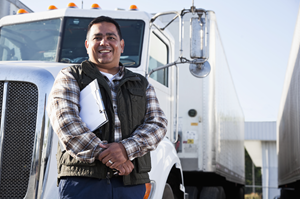 man smiling at camera standing in front of a semi truck