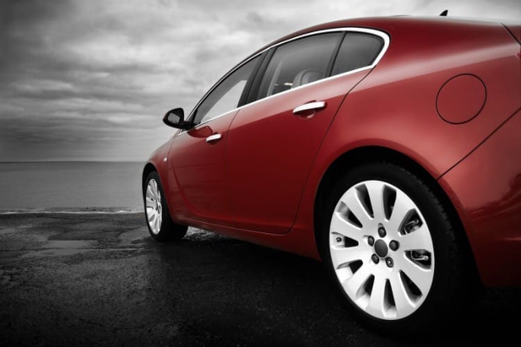 red car parked next to the ocean