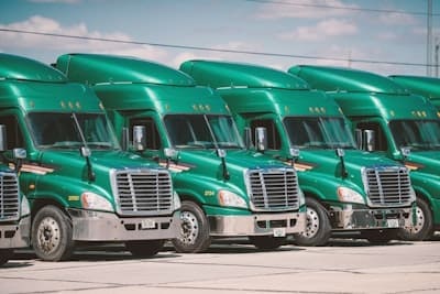 Four green semi trucks parked