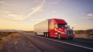 red tractor with white trailer driving on rural highway